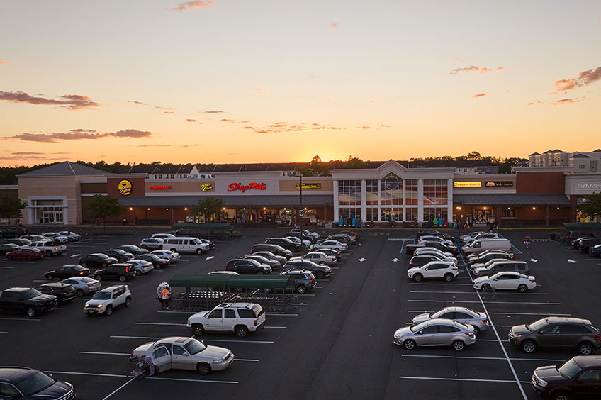 Image of Brick Commons shopping center with various shops and parking spaces.