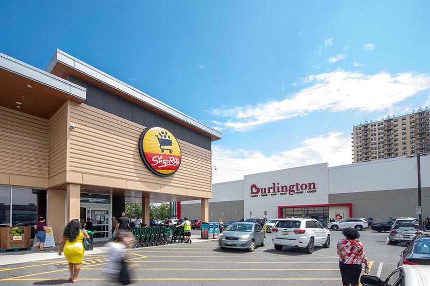 Image of Bruckner Commons shopping center with various shops and parking spaces.