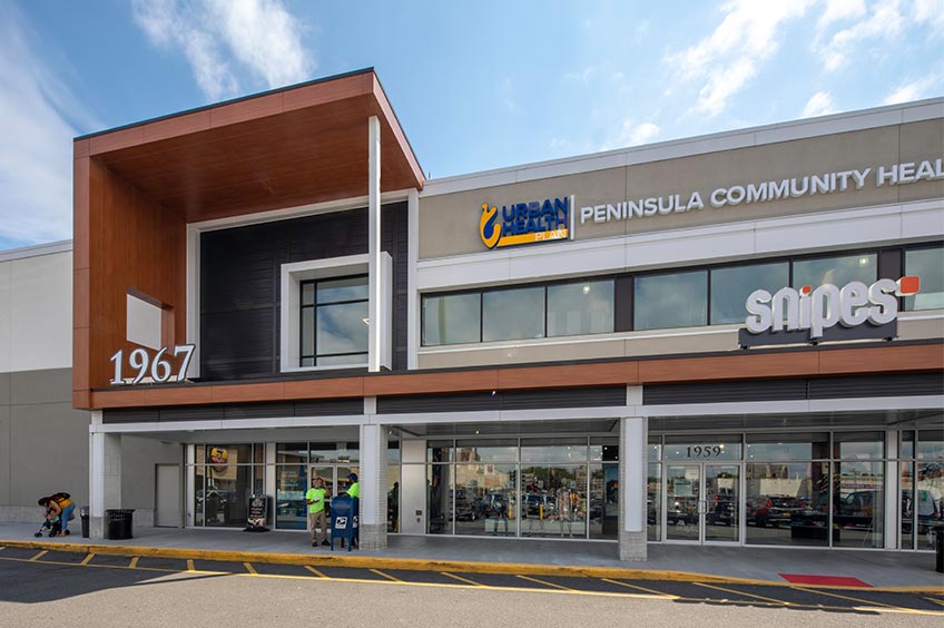 Sidewalk and shop storefront at Bruckner Commons shopping center.