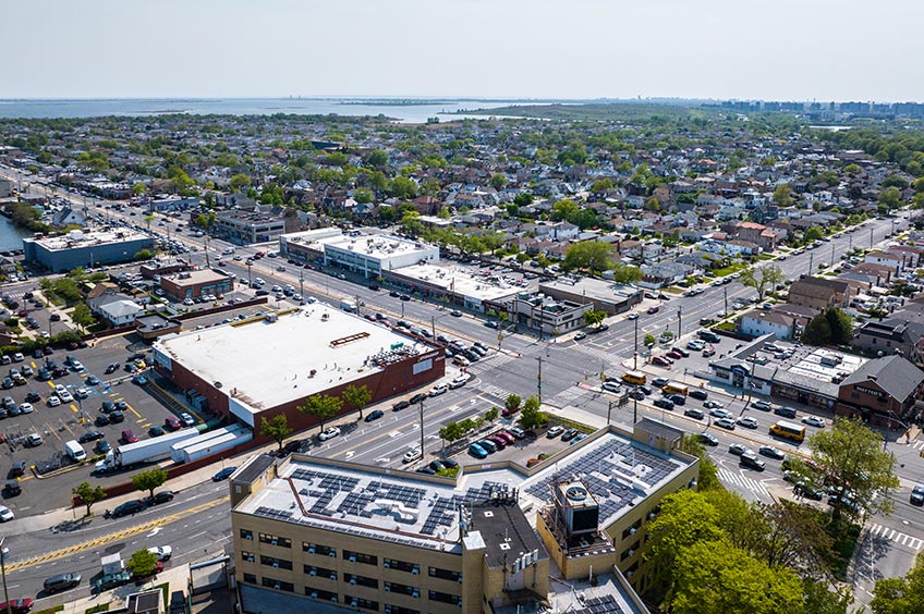 Overhead shot of Cross Bay Commons shopping center and its adjacent parking lot, captured from a high vantage point.