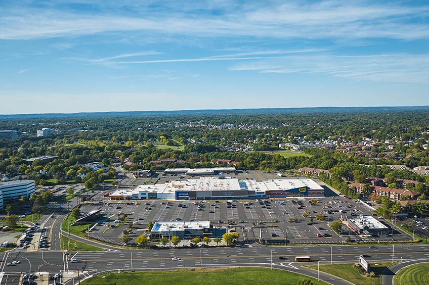 Aerial view of The Plaza at Woodbridge shopping center and its adjacent parking lot, captured from a high vantage point.